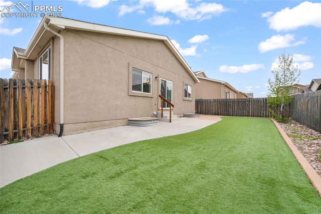 Image 44 of 50: Rear exterior featuring a stucco facade, gabled roofline, and a concrete pa
