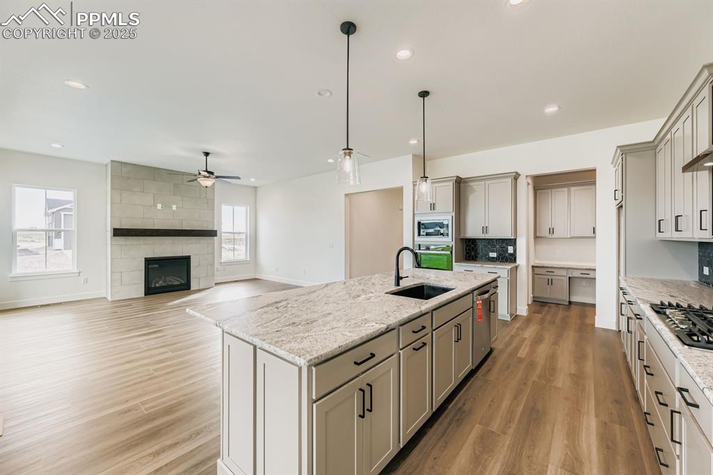 Image 10 of 27: Kitchen featuring decorative light fixtures, a center island with sink, lig