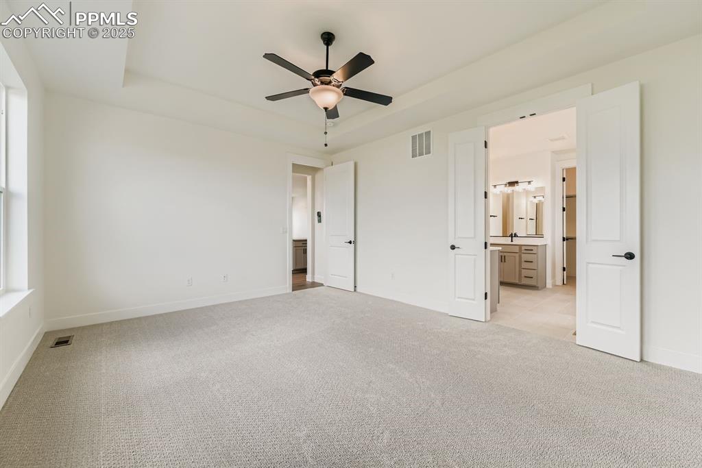 Image 12 of 27: Unfurnished bedroom with light colored carpet, a raised ceiling, a ceiling