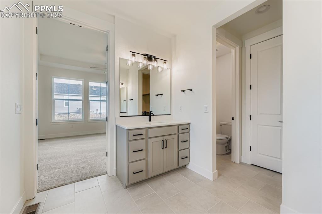 Image 15 of 27: Bathroom with vanity, light tile patterned floors, light colored carpet, an