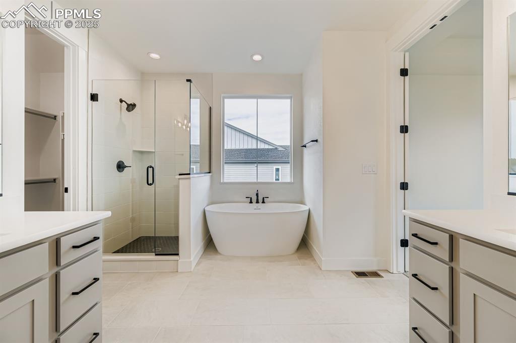 Image 16 of 27: Bathroom with two vanities, a shower stall, a freestanding bath, recessed l