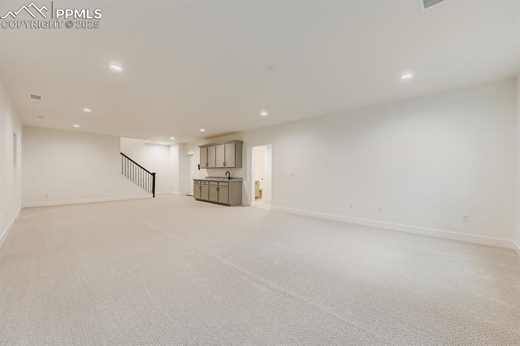 Image 21 of 27: Unfurnished living room featuring recessed lighting, stairway, and light ca