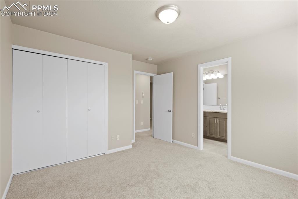 Image 10 of 35: Unfurnished bedroom with light colored carpet, a closet, and ensuite bath