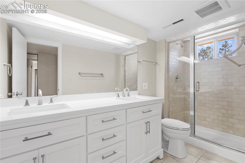 Image 22 of 35: Full bathroom with double vanity, a stall shower, and light tile patterned