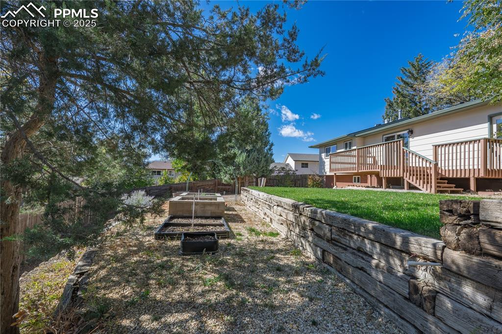 Image 30 of 35: Fenced backyard featuring a garden and a wooden deck