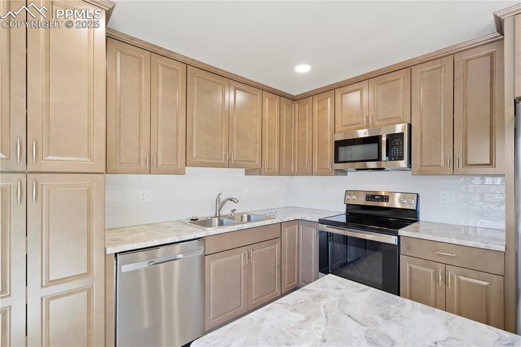 Image 4 of 35: Kitchen with stainless steel appliances, decorative backsplash, recessed li