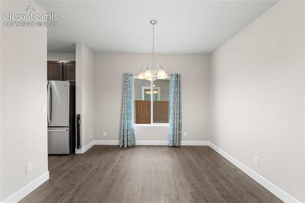 Image 10 of 42: Spacious room with wood-finish flooring, light neutral walls, and a promine