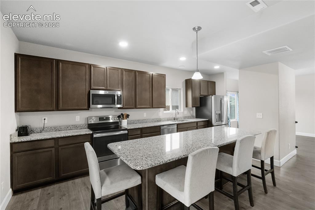 Image 11 of 42: Kitchen featuring a large island with granite countertops, stainless steel 
