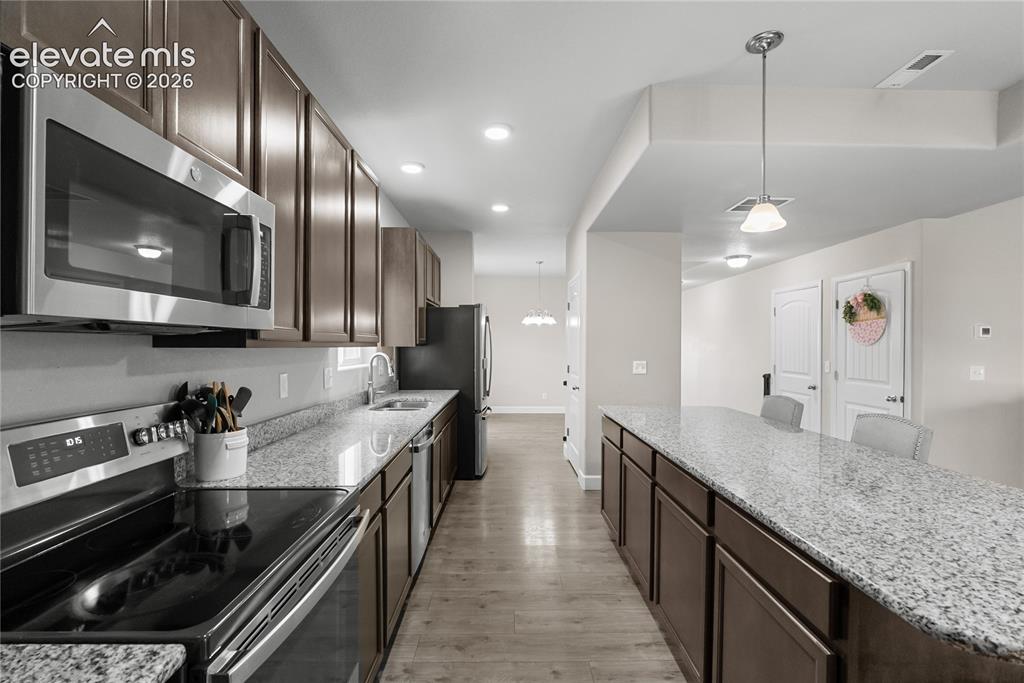 Image 13 of 42: Spacious kitchen featuring extensive granite countertops, wood-finish floor