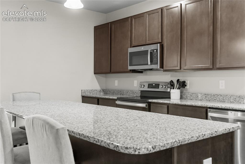 Image 15 of 42: Granite island with breakfast bar seating and matching perimeter countertop