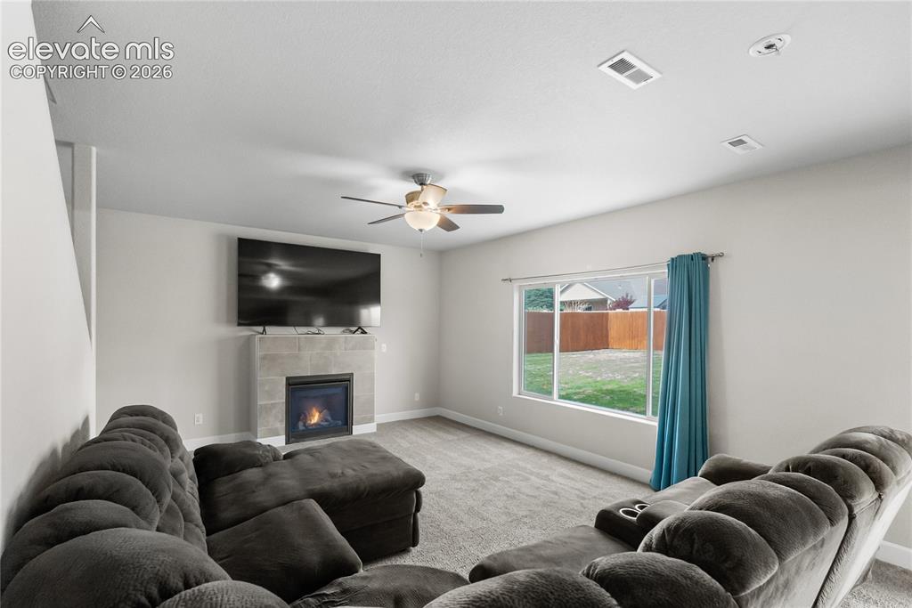 Image 16 of 42: Living space featuring a gas fireplace with a tiled surround, a large windo