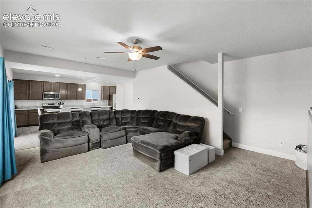 Image 17 of 42: Open-concept living space featuring light gray carpeting and a ceiling fan 
