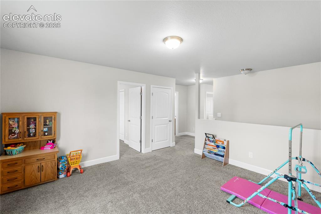 Image 20 of 42: Spacious carpeted room featuring multiple doorways with white trim, a half-