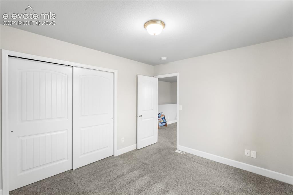 Image 22 of 42: Room with light gray walls, gray carpeting, and white baseboards