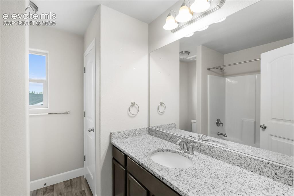 Image 23 of 42: Bathroom vanity featuring a speckled countertop, an undermount sink with a 