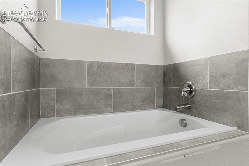 Image 29 of 42: White drop-in bathtub with brushed nickel fixtures