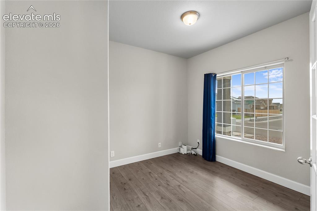 Image 4 of 42: Bright room featuring a large window with grid panes, wood-finish flooring,