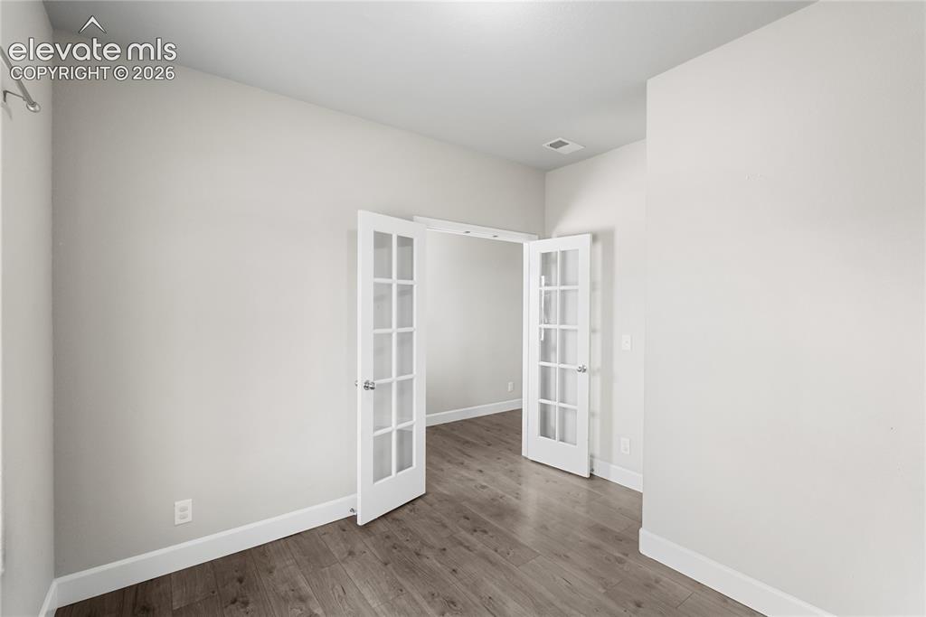 Image 5 of 42: Interior room featuring French doors with mullioned glass panels, wood-fini