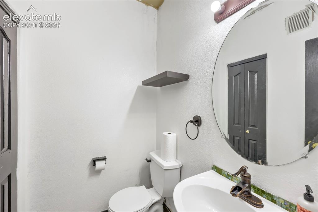 Image 15 of 17: White ceramic toilet, pedestal sink with bronze-finish faucet, circular mir