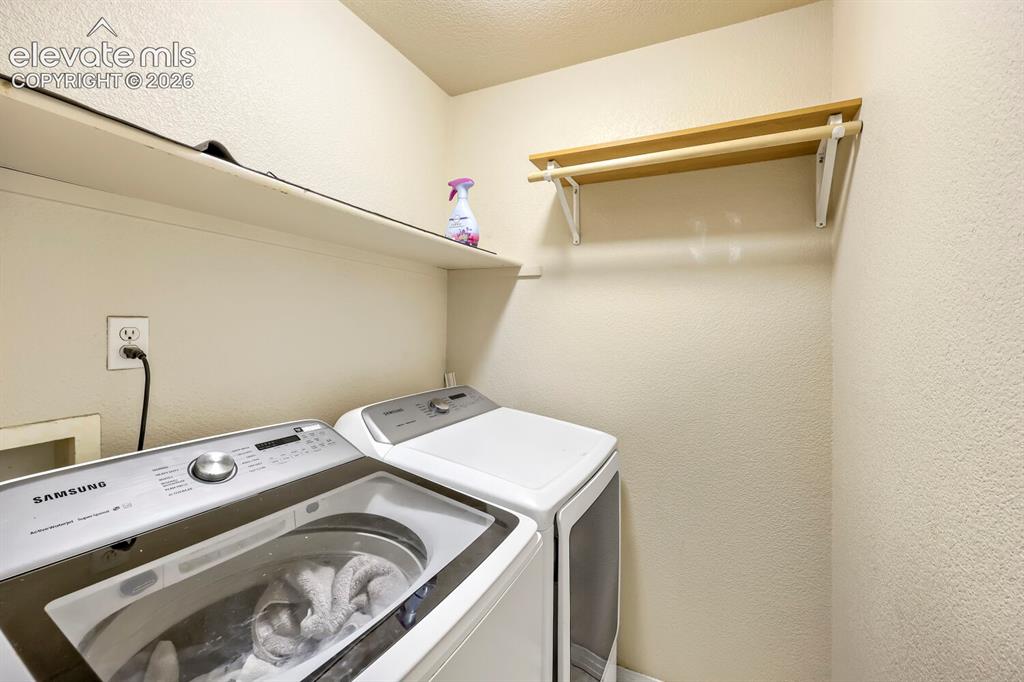 Image 16 of 17: Dedicated laundry space featuring a built-in shelving unit and a clothes ha