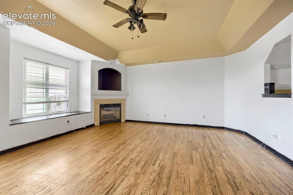 Image 2 of 17: Wood-finish flooring, recessed fireplace with tile surround, built-in media
