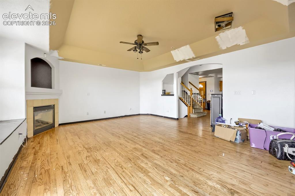 Image 3 of 17: Wood-finish flooring throughout, tray ceiling with a ceiling fan, and an ar