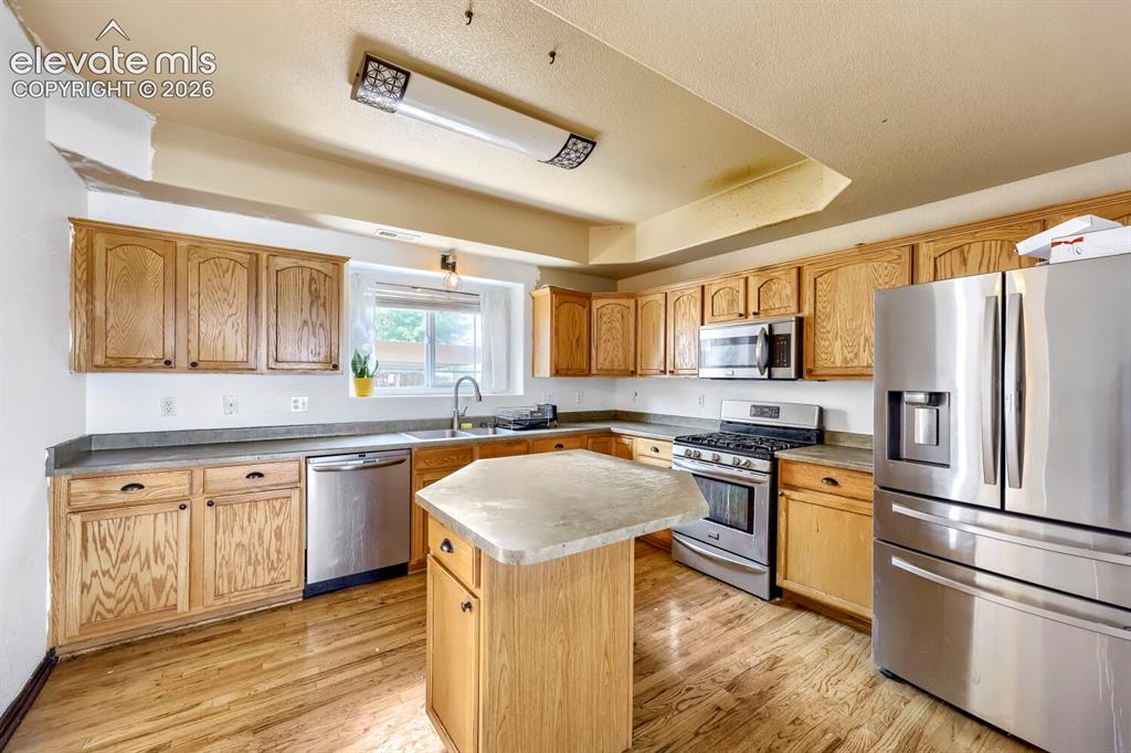 Image 5 of 17: Kitchen featuring wood-finish cabinetry, stainless steel appliances, a cent