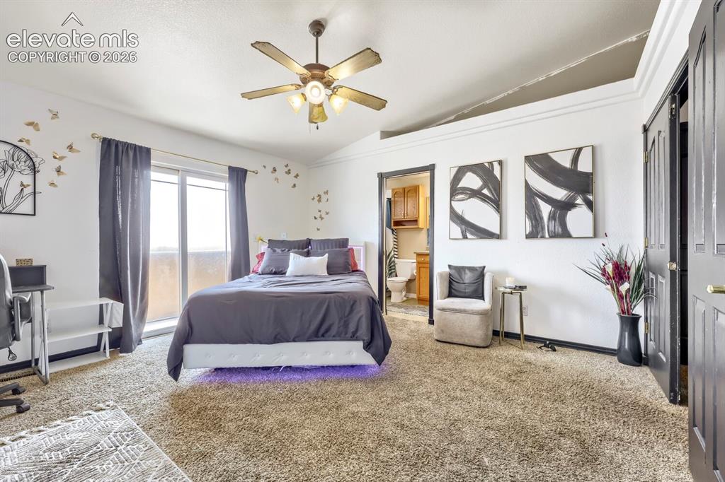 Image 6 of 17: Carpeted room featuring a vaulted ceiling with a ceiling fan, sliding glass