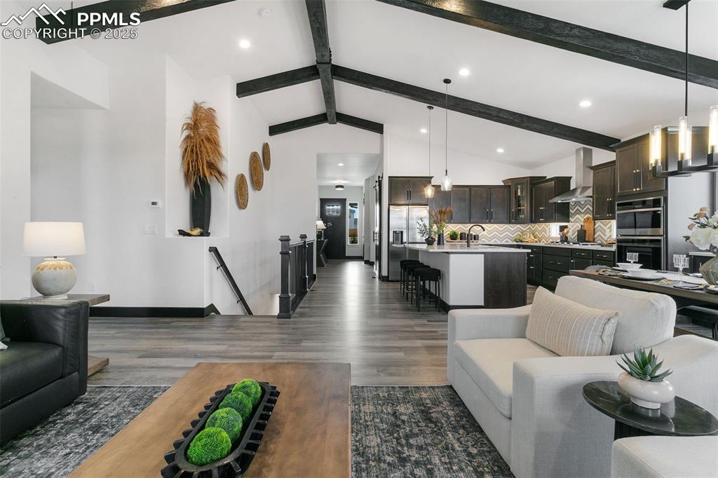 Image 13 of 23: Living area with beamed ceiling, dark wood-style floors, high vaulted ceili