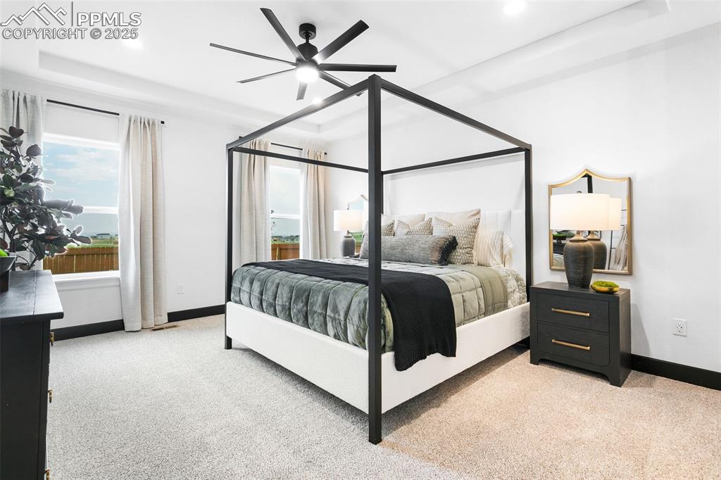 Image 15 of 23: Bedroom with light carpet, a ceiling fan, recessed lighting, and a raised c