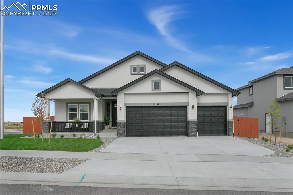 Image 2 of 23: View of front of house with stone siding, stucco siding, a porch, and drive