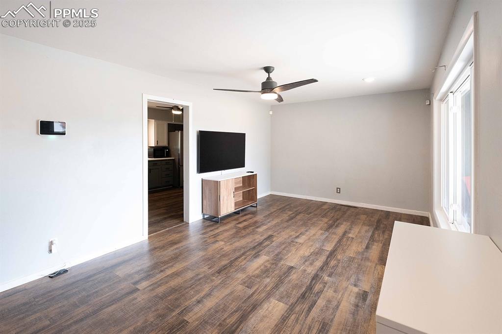 Image 10 of 43: View from front entrane across the living room door frame is to the kitchen