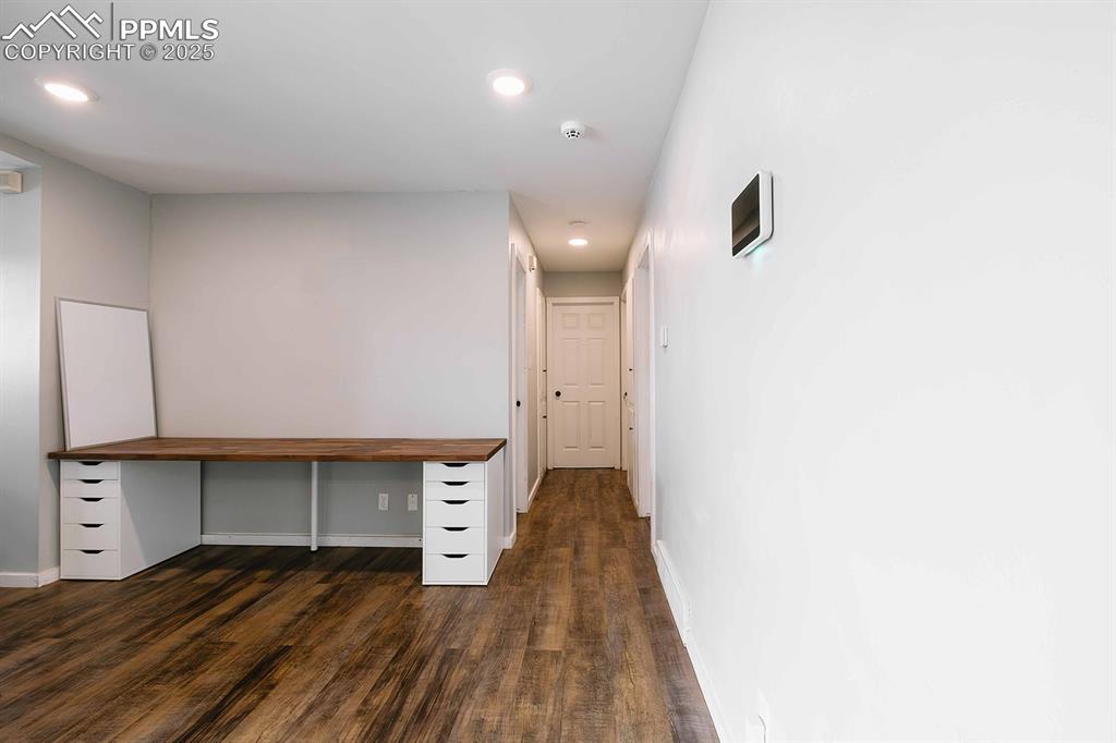 Image 9 of 43: Office space has been niched out in the corner of the living room. Hall to