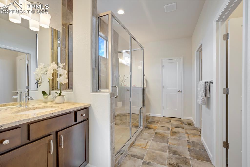 Image 19 of 50: Primary suite with mud-set shower + bench + Dual granite topped vanities