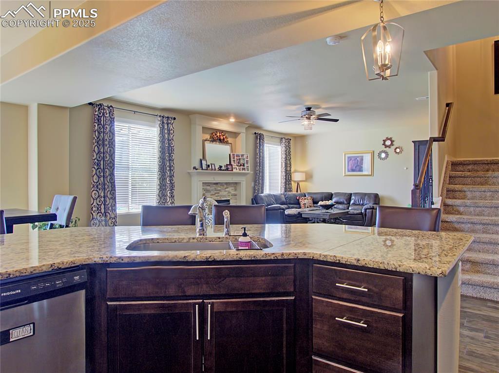 Image 10 of 30: Kitchen with dark brown cabinetry, dishwasher, decorative light fixtures, a