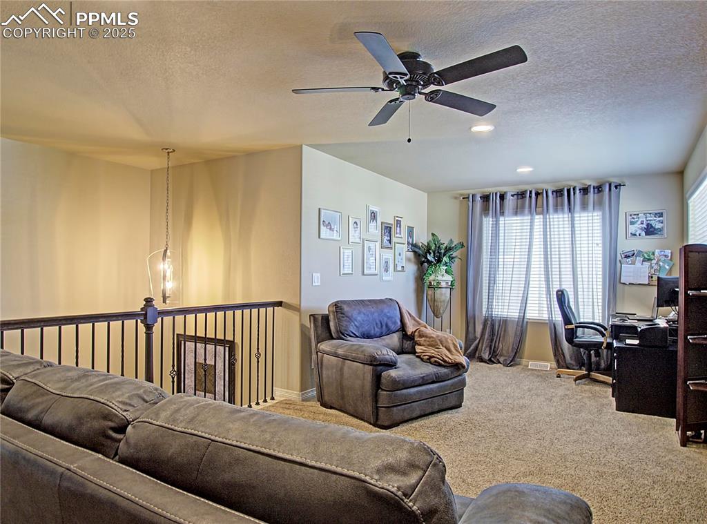 Image 17 of 30: Carpeted living area featuring a textured ceiling, a chandelier, ceiling fa