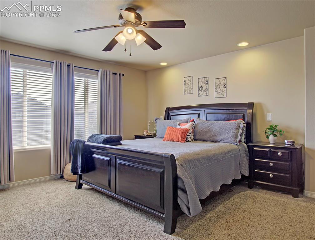 Image 23 of 30: Bedroom with light colored carpet, ceiling fan, and recessed lighting