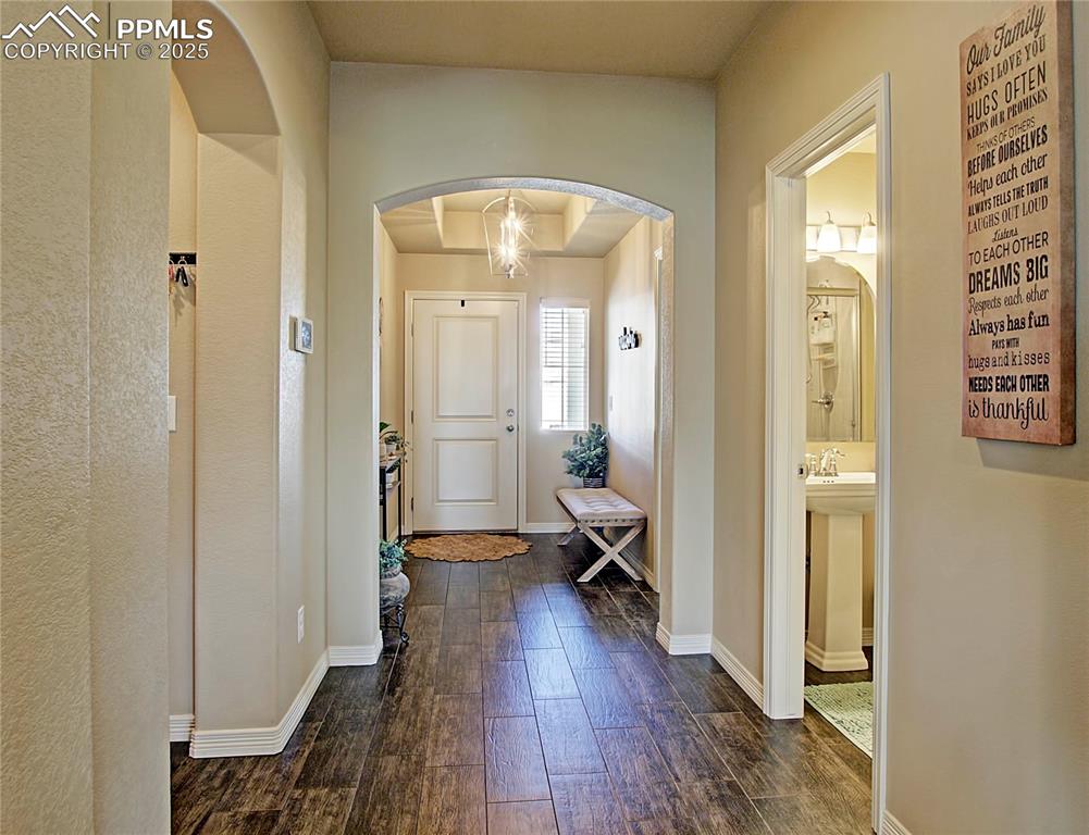 Image 4 of 30: Foyer entrance with arched walkways and dark wood-style flooring