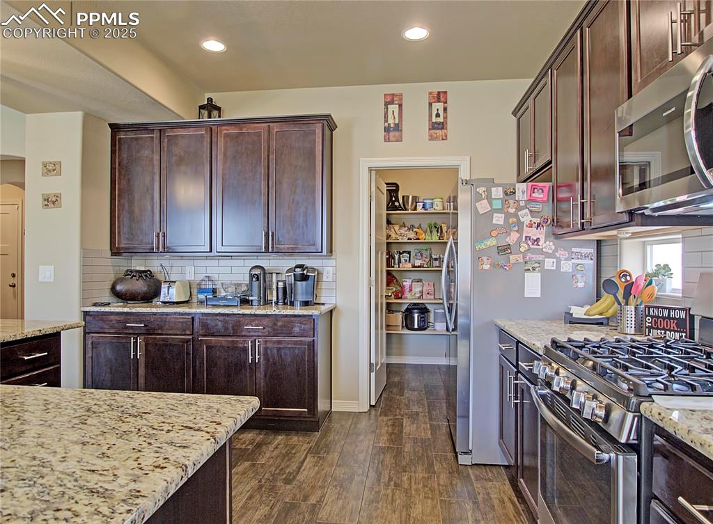 Image 9 of 30: Kitchen with decorative backsplash, appliances with stainless steel finishe