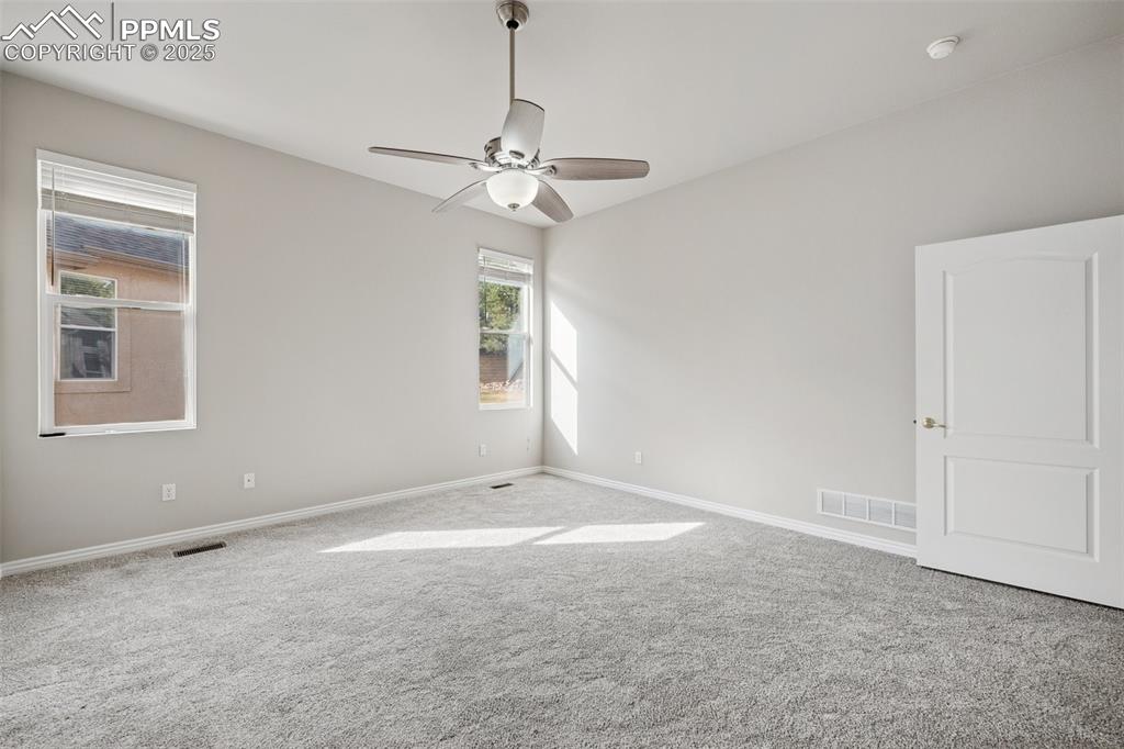 Image 22 of 29: Unfurnished room with carpet floors, visible vents, a ceiling fan, and base