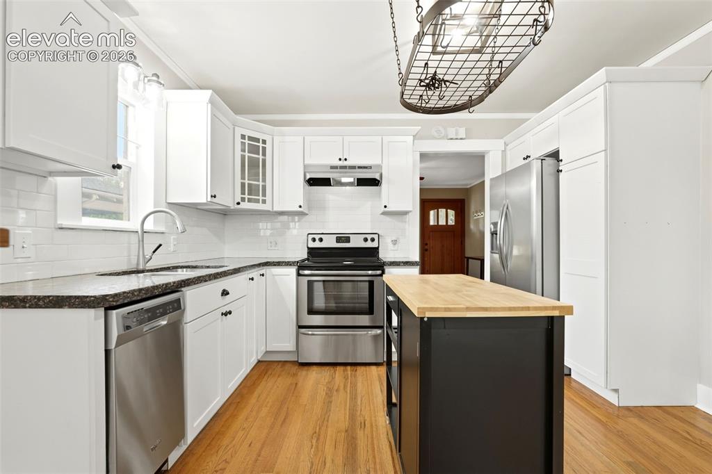 Image 10 of 40: Well-appointed kitchen featuring white cabinetry, dark stone-finish counter