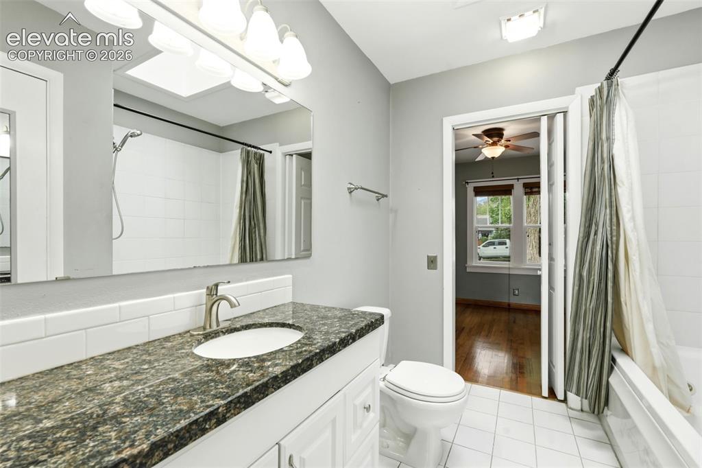 Image 15 of 40: Bathroom featuring a vanity with a dark granite countertop, a single basin