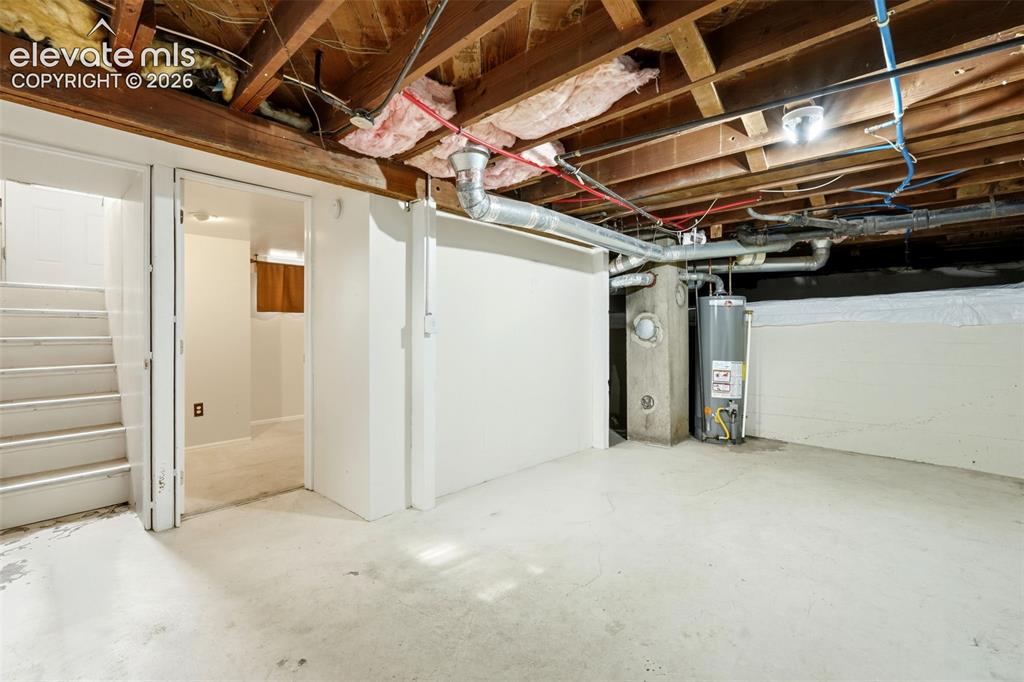 Image 21 of 40: Utility room featuring a water heater, exposed ceiling joists, and concrete