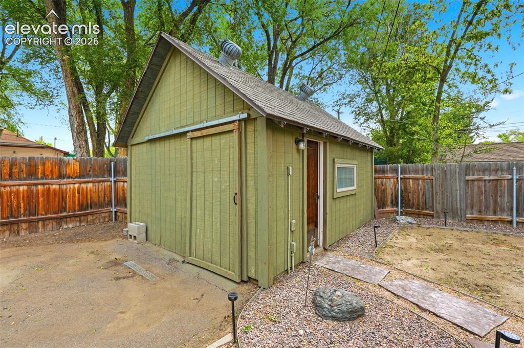 Image 24 of 40: Green outbuilding featuring a pitched roof, a sliding barn door, and a sing