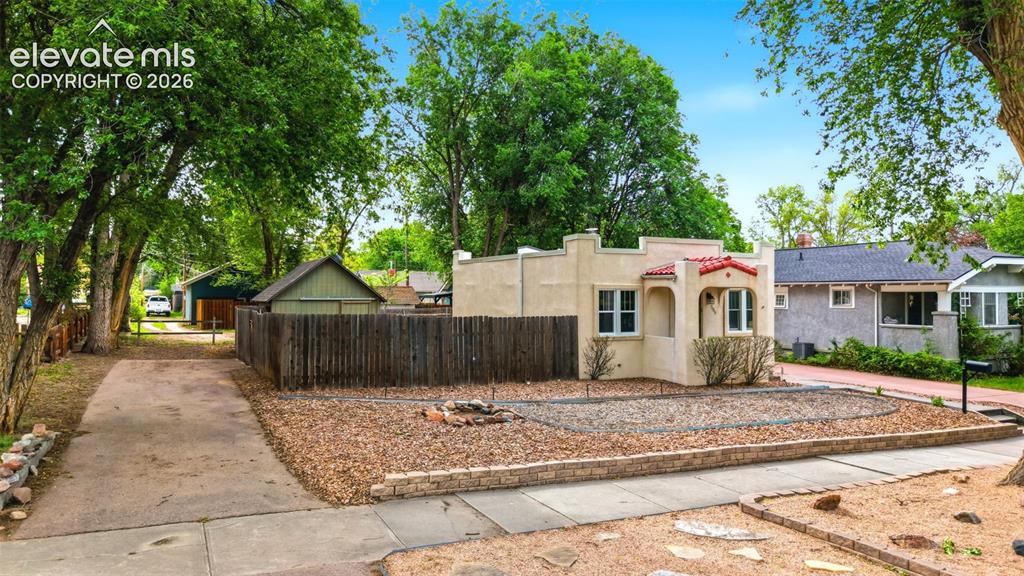 Image 26 of 40: Stucco exterior with a red tile roof accent, arched entryway, and white-fra
