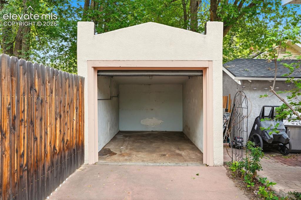 Image 27 of 40: Single-car garage structure with a stucco exterior finish and concrete floo