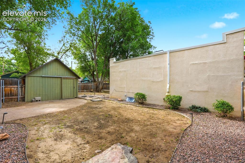 Image 31 of 40: Spacious backyard featuring a detached green barn with sliding doors, a gra