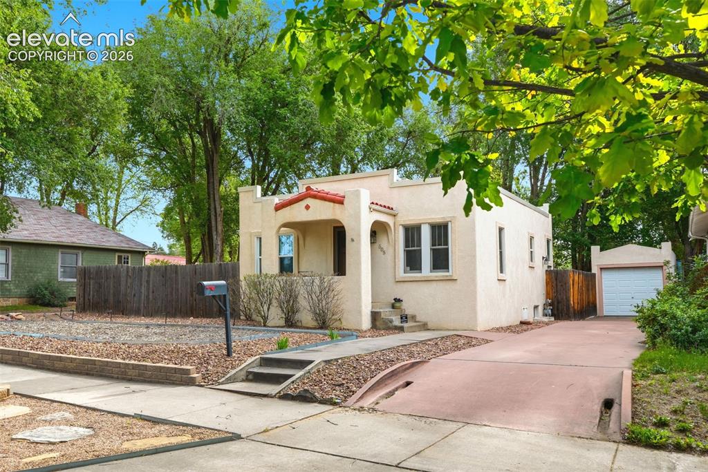 Image 32 of 40: Stucco exterior with a terracotta tile roof accent and arched entry