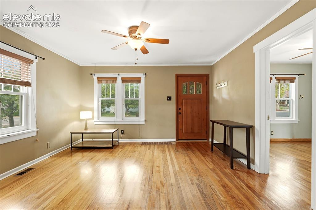 Image 6 of 40: Hardwood flooring throughout, with a paneled wooden entry door featuring gl