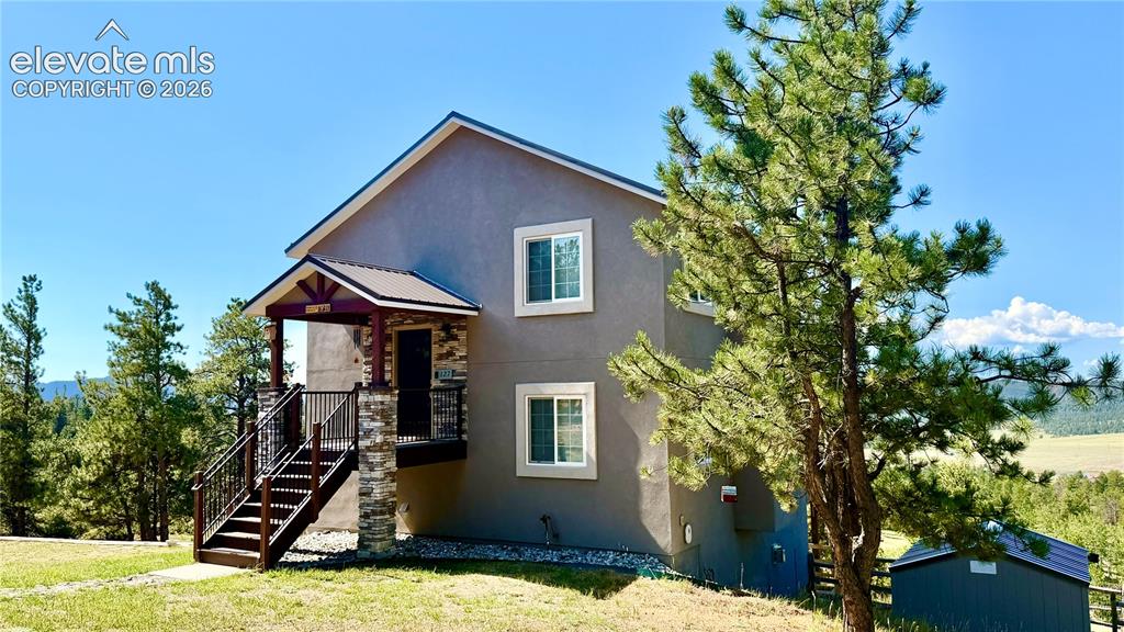 Caption: Two-story stucco exterior with a stone-clad foundation and covered entry